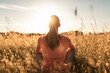 © kieferpix - Young female sitting in wheat field feeling grateful, joyful outdoors in the sunrise