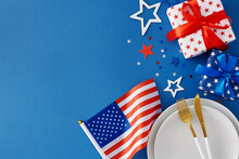 American Independence Day Table Arrangement Concept. Top View Flat Lay Of Plates, Cutlery, National Flag, Gift Boxes And Patriotic Stars On Blue Background With Space For Greetings Or Promo