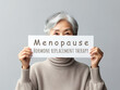 An older Asian woman holding up paper with text Menopause, Hormone Replacement Therapy. Generative AI.