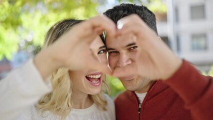 Poster - Man and woman couple smiling confident doing heart gesture with hands at park