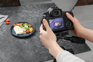 Poster - Woman taking picture of mozzarella salad on table in professional photo studio, closeup. Food photography