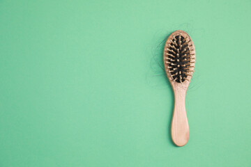 Wall Mural - Wooden brush with lost hair on green background, top view. Space for text