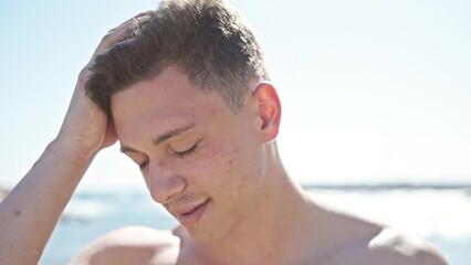 Sticker - Young hispanic man tourist standing with relaxed expression combing hair with hands at seaside