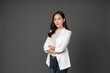 © Nutchapong Wuttisak - An Asian female executive with long hair stood with her arms crossed, confident and determined. She wore a white suit. and stand to take pictures with a gray scene in the studio