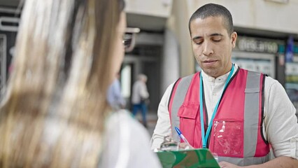 Canvas Print - Young hispanic man volunteer speaking with person at street