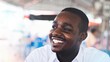 © arrowsmith2 - Happy african man wearing white shirt smiling openly in community area. Positive black ethnic man with healthy white teeth, portrait of smiling teeth close up