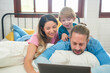 © sutthinon602 - Happy family people leisure in bedroom together. Father and mother with son relaxing and using laptop on bed