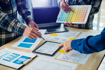  UX developer and ui designer brainstorming about mobile app interface wireframe design with customer breif and color code at modern office..