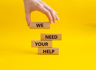 We need your help symbol. Wooden blocks with words We need your help. Beautiful yellow background. Businessman hand. Business and We need your help concept. Copy space.