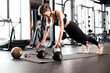 © ty - Portrait of a muscular woman on a plank position with kettlebell at gym.