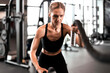 © ty - Fit woman using battle ropes during strength training at the gym.