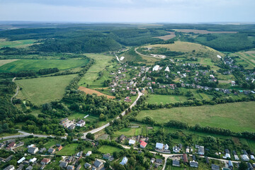 Wall Mural - Aerial landscape view of green cultivated agricultural fields with growing crops and distant village houses