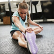 © Matthew C/peopleimages.com - Stretching, warm up and woman in gym for exercise, training and fitness on floor for workout. Health, sports and female person stretch legs in sport center for wellness, performance and flexibility