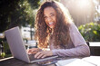 © Matthew C/peopleimages.com - Portrait, woman and student with a laptop, outdoor and typing with a smile, connection and online reading. Face, female person or girl in a cafe, pc or technology with education, email and university