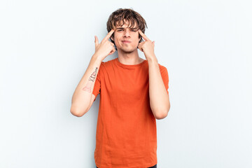 Wall Mural - Young caucasian man isolated on blue background focused on a task, keeping forefingers pointing head.