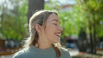 Poster - Young blonde woman smiling confident combing hair with hands at park