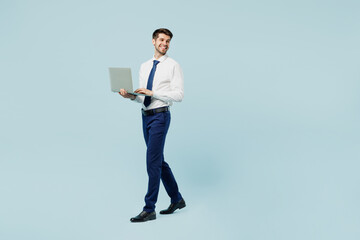 Full body side view young employee IT business man corporate lawyer wearing classic formal shirt tie work in office hold use work on laptop pc computer isolated on plain pastel blue background studio.