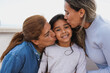 Latin multi generational family having tender moment outdoor - Female child smiling on camera while mother and grandmother kissing her