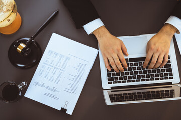 Wall Mural - Top view lawyer or judge working on his desk with laptop at law firm or court, drafting legal documents with fairness and ethical judgment for lawsuits and litigation. Equilibrium