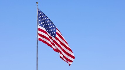 Wall Mural - us flag on a flagpole blowing in the breeze.