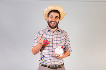 Brazilian man wearing festa junina clothes. Arraial, Feast of Saint John. with piggy bank and coin.