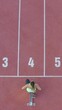 Vertical video of caucasian female athlete alone on the athletic track, sprint running in line four, aerial directly above view.