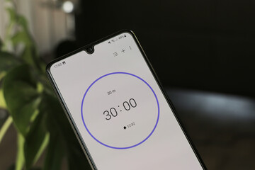 A phone with a white 30-minute timer on a blurry background