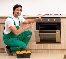 Wall Mural - Young contractor repairing oven in kitchen