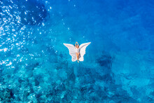 An Aerial View Of The Girl. Rest On The Beach. Swimming On An Inflatable Butterfly. Sea Relaxation And Travel. Azure Water On The Sea. A Bright Sunny Day During A Summer Vacation.