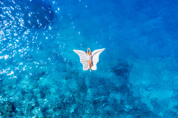 Wall Mural - an aerial view of the girl. rest on the beach. swimming on an inflatable butterfly. sea relaxation a