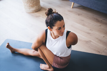 Wall Mural - Young Caucasian woman enjoying morning workout for retreat healing in hatha asana mantras, flexible female yogi in sportive clothes training and exercising during daytime in home apartment