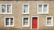 Traditional mid-century  roughcast or pebbledash facade of residential building exterior with red front door in the Scottish village of Aberdour, Fife, Scotland, UK.