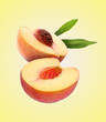 © New Africa - Juicy fresh halved peach with green leaves falling on pale yellow background