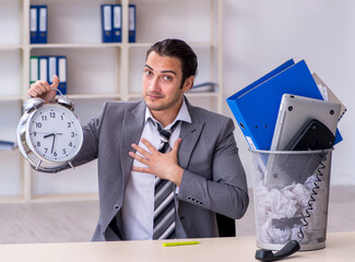 Fired young businessman with recycle bin in time management conc