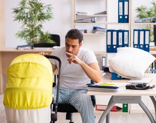 Wall Mural - Young male employee looking after newborn at workplace