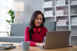 © amnaj - Cute Asian young woman red shirt is using laptop computer sitting on the floor in the living room, watching movie, listening to music, shopping online, watching live broadcast.