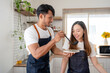 © amnaj - Asian couple happily prepare ingredient for breakfast in modern and stylish kitchen. Young Asian couple happily wearing apron and cooking together.