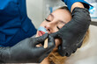 Young beautiful female client getting hot sugar wax epilation on upper lip of face in salon