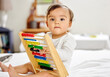 © Anela Ramba/peopleimages.com - Abacus, bed and portrait of baby with toy for learning, child development and motor skills. Family home, newborn and face of adorable child with educational toys, counting beads and fun in bedroom