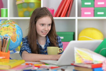 girl with cup using laptop at home at desk