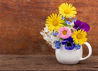 Poster - small spring bouquet. Bouquet of wild flowers in a small vase on a wooden table. Bouquet of daisies. Country style.