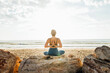 © Westend61 - Woman practicing yoga with hands clasped behind back sitting at beach