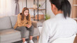 © golubovy - Psychologist consultation. Mental specialist. Unhappy teenage girl complaining life sitting sofa on psychotherapist therapy session light room interior.