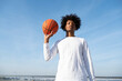 © Westend61 - Athlete holding basketball in front of sky