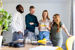 © Westend61 - Happy multiracial colleagues watching mobile phone in office