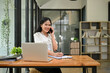 © bongkarn - Attractive of young Asian businesswoman is talking on the phone at her desk