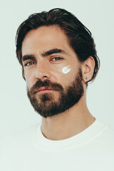 Wall Mural - Embracing male skincare with confidence, man applying moisturizing beauty cream on his face