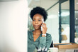 © Graham Fielies/peopleimages.com - Phone call, black woman and business accountant on computer in conversation with contact. Smartphone, serious and African female professional or auditor talking, listening or communication in office.