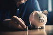 © FotoIdee - Close-Up Of A Pensioners Hand Stacking Coins Next To A Piggy Bank To Save Money For Future Investments And To Supplement His Insufficient Pension - Generative AI