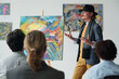 © pressmaster - Artist presenting his picture to group of people at art exhibition in gallery